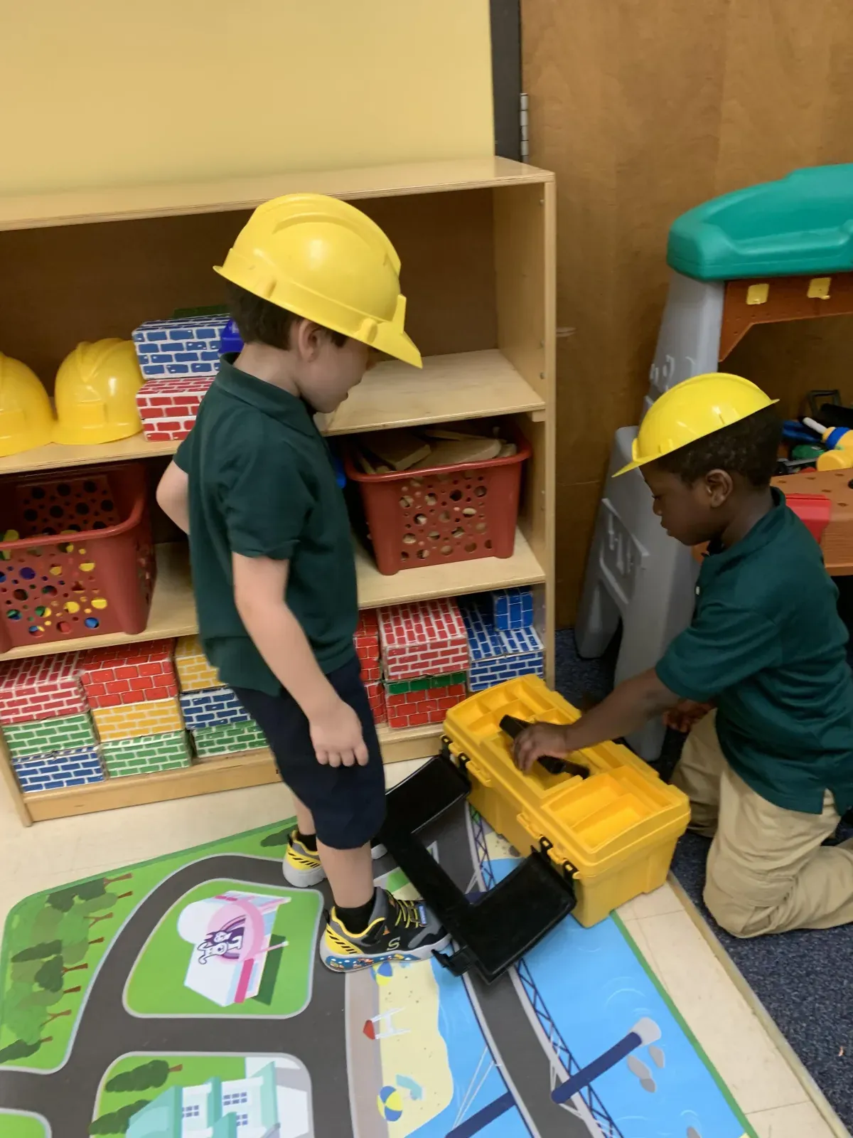 Two preschoolers in hard hats building together at the classroom construction center